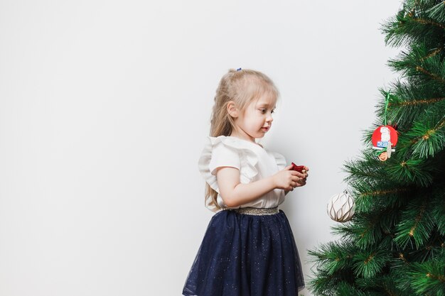 Pequeña niña decorando árbol de navidad