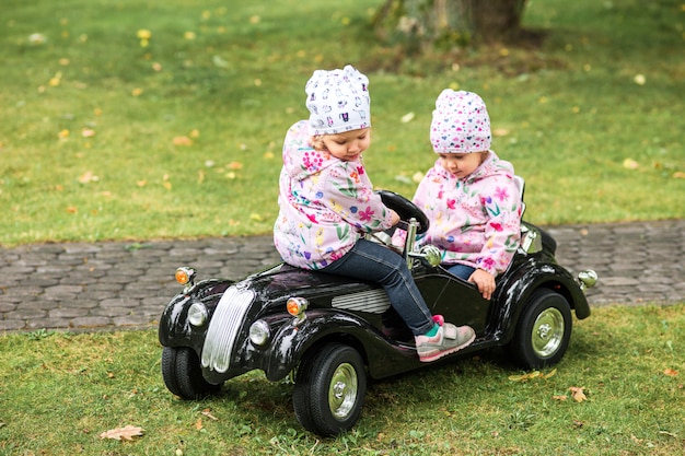 Foto gratuita la pequeña niña jugando en el coche contra la hierba verde