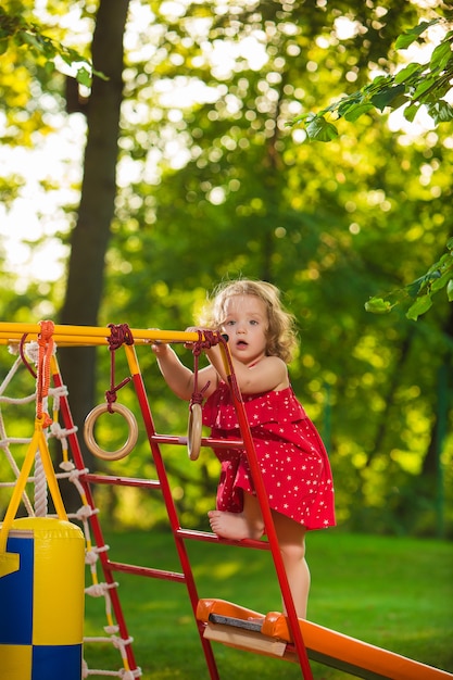 La pequeña niña jugando en el patio al aire libre contra la hierba verde