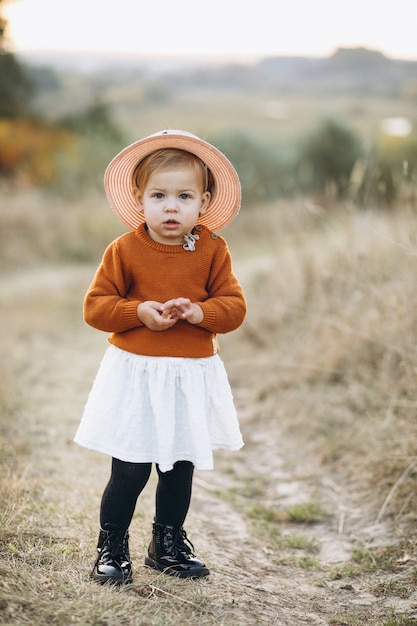 Pequeña niña linda afuera en el parque, tiempo de otoño