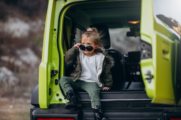 Pequeña niña linda sentada en la parte trasera del coche