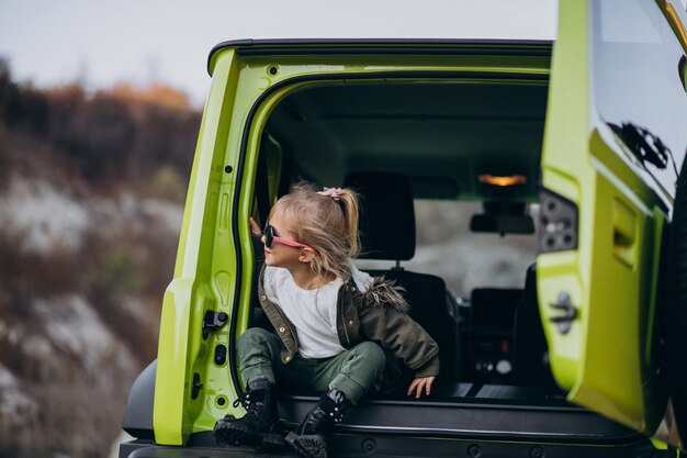 Pequeña niña linda sentada en la parte trasera del coche