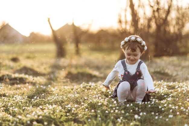 La pequeña niña sentada cerca de las flores