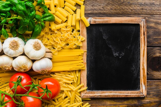 Pequeña pizarra cerca de ingredientes de pasta