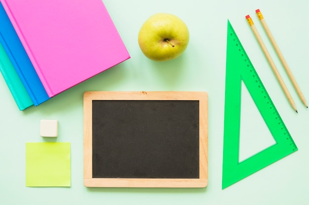 Pequeña pizarra con papelería y manzana