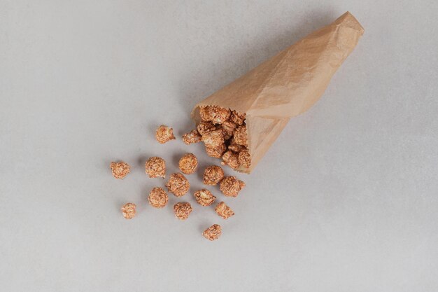 Pequeña porción de dulces de palomitas de maíz en un envoltorio de papel sobre una mesa de mármol.