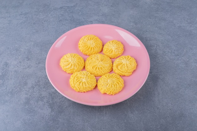 Una pequeña porción de galleta en un plato sobre una mesa de mármol.