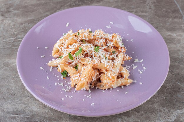 Una pequeña porción de pasta penne, sobre el mármol.