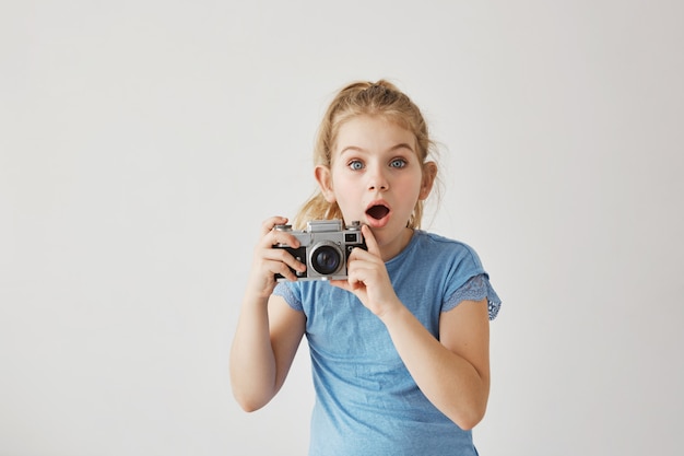 Foto gratuita la pequeña señorita rubia con ojos azules estaba tomando fotos familiares de los padres con una cámara de cine cuando papá se resbaló y se cayó. niño que parece asustado de que el padre se lastime.