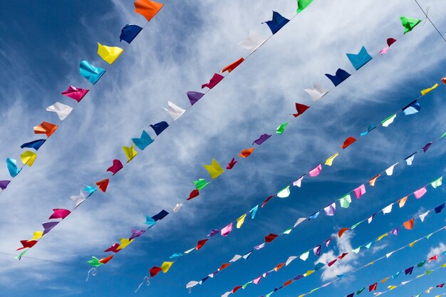 Pequeñas banderas coloridas lindas en la cuerda que cuelga afuera para el día de fiesta con el cielo azul brillante fondo blanco de las nubes. Italia, Cerdeña.