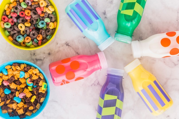 Foto gratuita pequeñas botellas de leche con tazones de cereal en la mesa.