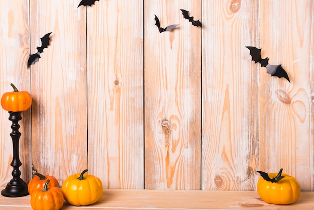 Pequeñas calabazas y murciélagos cerca de la pared