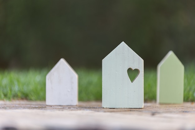 Pequeñas casas de madera con un corazón en el grande que simboliza el amor familiar y la seguridad en el hogar.