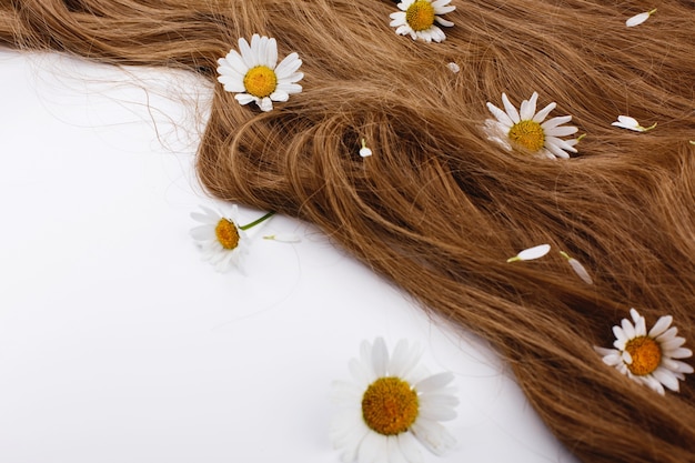 Pequeñas flores blancas se encuentran en los rizos de cabello castaño