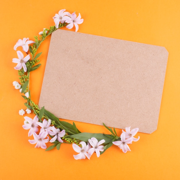 Foto gratuita pequeñas flores con hojas verdes y papel en blanco.