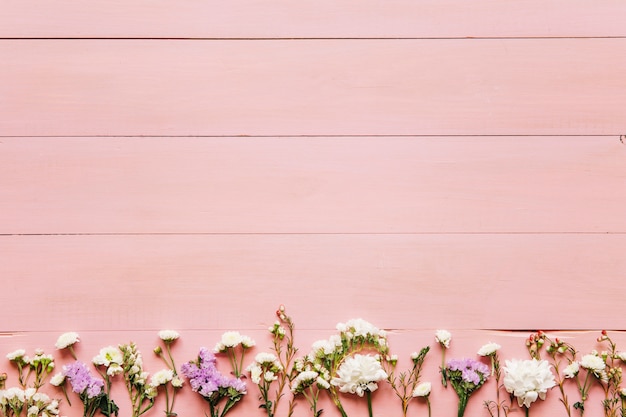 Foto gratuita pequeñas flores en la mesa de madera rosa