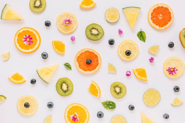 Pequeñas hojas y flores cerca de rebanadas de frutas