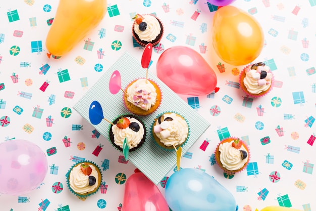 Foto gratuita pequeñas magdalenas con globos en mesa