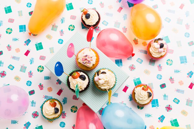 Pequeñas magdalenas con globos en mesa