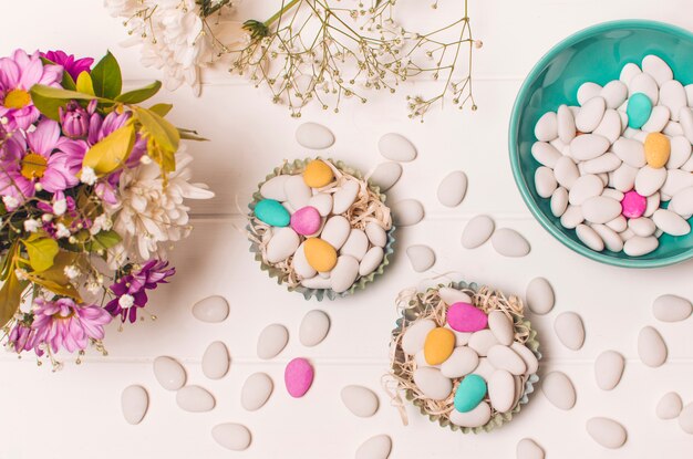 Pequeñas piedras brillantes en cestas y cuenco cerca del ramo de flores