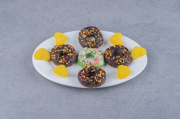 Foto gratuita pequeñas rosquillas y mermeladas cuidadosamente dispuestas en una bandeja sobre una superficie de mármol