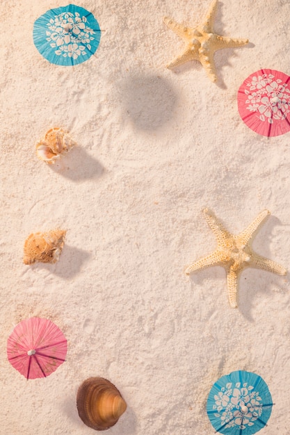 Foto gratuita pequeñas sombrillas con conchas en la playa.