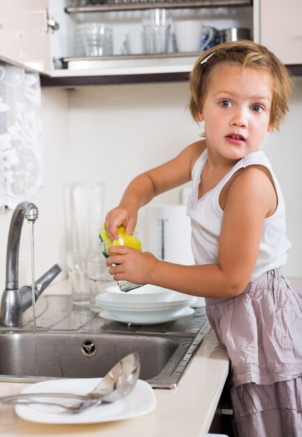 Pequeñas tareas de niña lavar los platos
