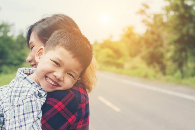 Pequeño abrazo muchacho asiático lindo con su madre y sonriendo a la cámara hap