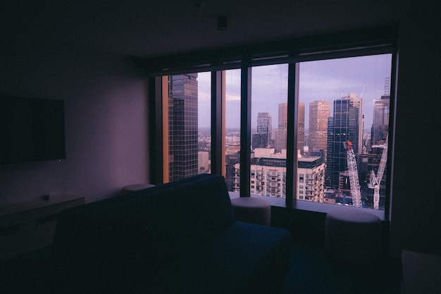 Foto gratuita pequeño apartamento con un gran ventanal con vistas a la arquitectura urbana de la ciudad.