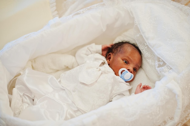 Pequeño bebé afroamericano recién nacido acostado en la cama