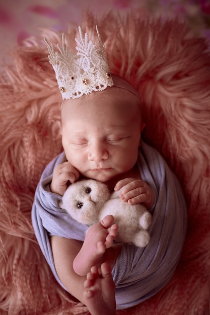 Foto gratuita el pequeño bebé con corona se encuentra en la canasta