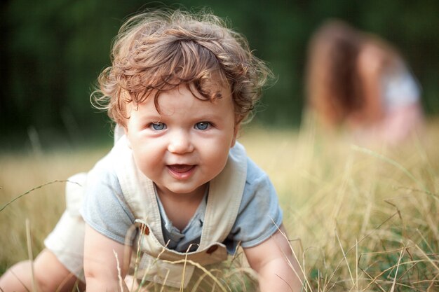 El pequeño bebé en la hierba en día soleado de verano.