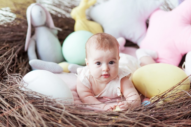 Pequeño bebé lindo con los huevos de Pascua coloridos y el conejo del juguete que mienten en jerarquía.