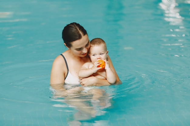 Pequeño bebé lindo. Madre con hijo. Familia jugando en un agua