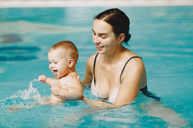 Pequeño bebé lindo. Madre con hijo. Familia jugando en un agua