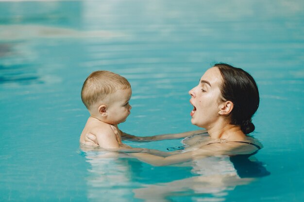 Pequeño bebé lindo. Madre con hijo. Familia jugando en un agua