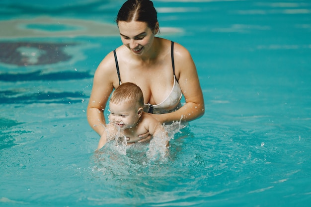 Pequeño bebé lindo. Madre con hijo. Familia jugando en un agua