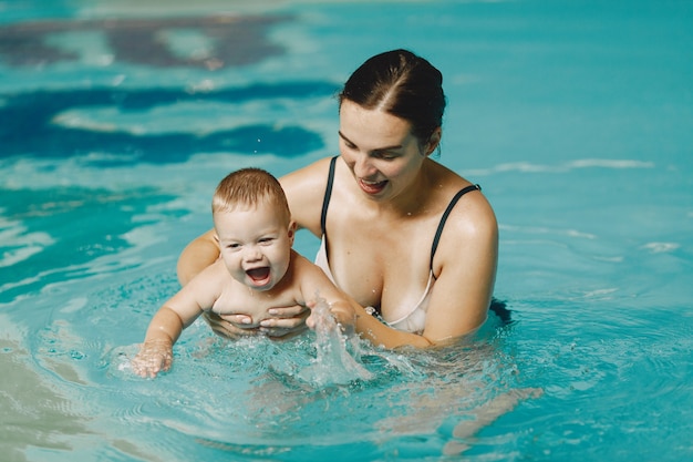 Pequeño bebé lindo. Madre con hijo. Familia jugando en un agua