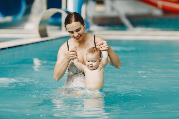 Pequeño bebé lindo. Madre con hijo. Familia jugando en un agua