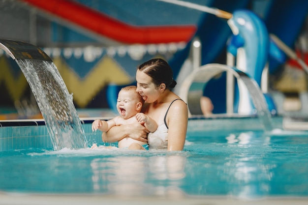 Pequeño bebé lindo. Madre con hijo. Familia jugando en un agua