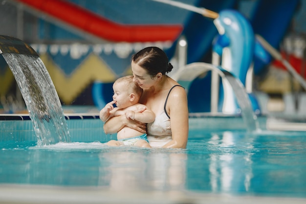 Pequeño bebé lindo. Madre con hijo. Familia jugando en un agua