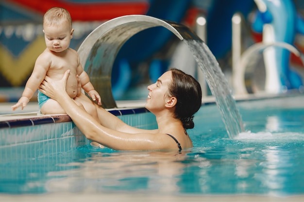 Pequeño bebé lindo. Madre con hijo. Familia jugando en un agua