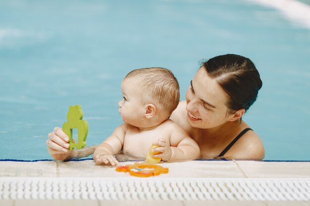 Pequeño bebé lindo. Madre con hijo. Familia jugando en un agua