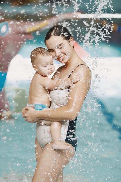 Pequeño bebé lindo. Madre con hijo. Familia jugando en un agua