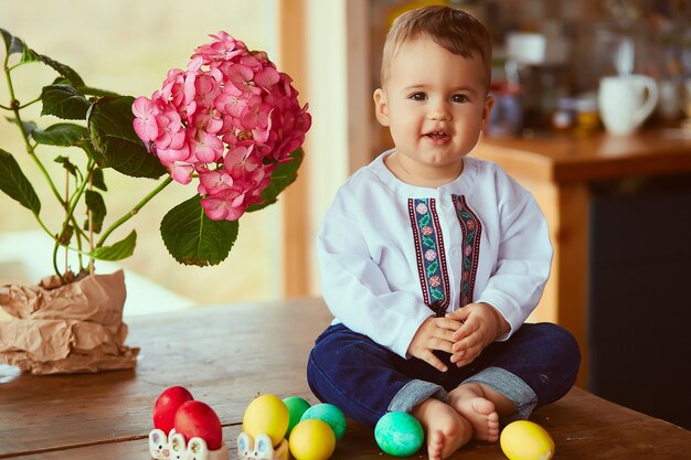 El pequeño bebé se sienta cerca de los huevos de Pascua