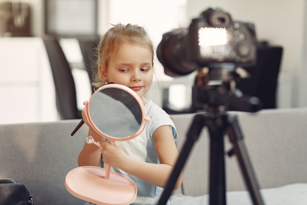 Pequeño blogger lindo con cosméticos grabando video en casa