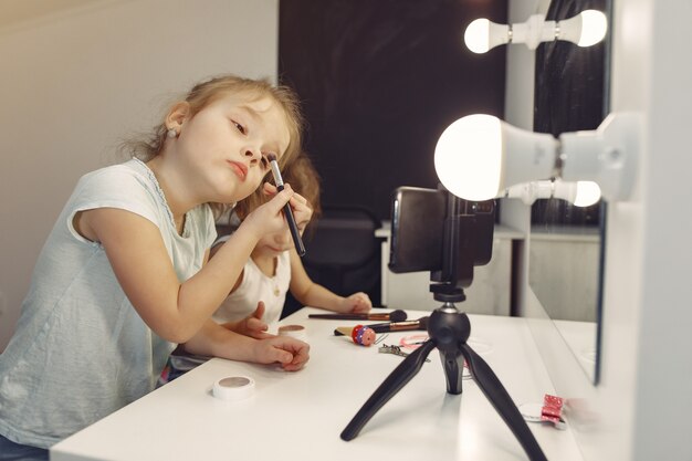 Pequeño blogger lindo con cosméticos grabando video en casa