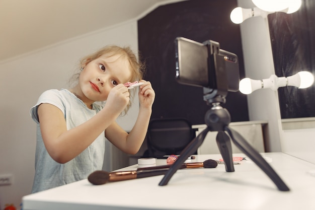 Pequeño blogger lindo con cosméticos grabando video en casa