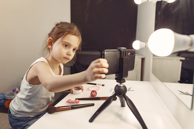 Pequeño blogger lindo con cosméticos grabando video en casa