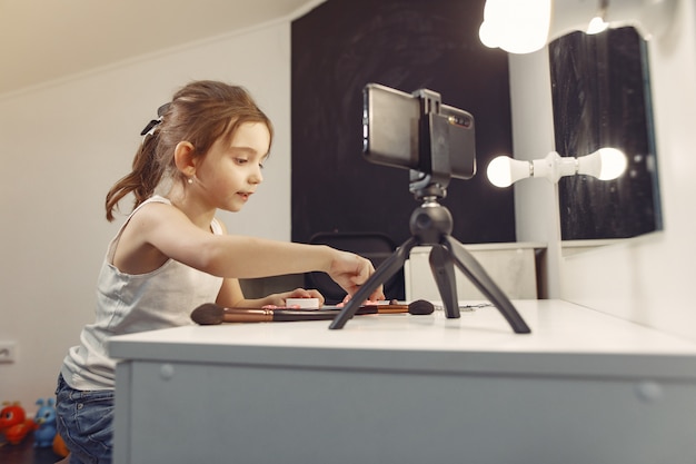 Pequeño blogger lindo con cosméticos grabando video en casa